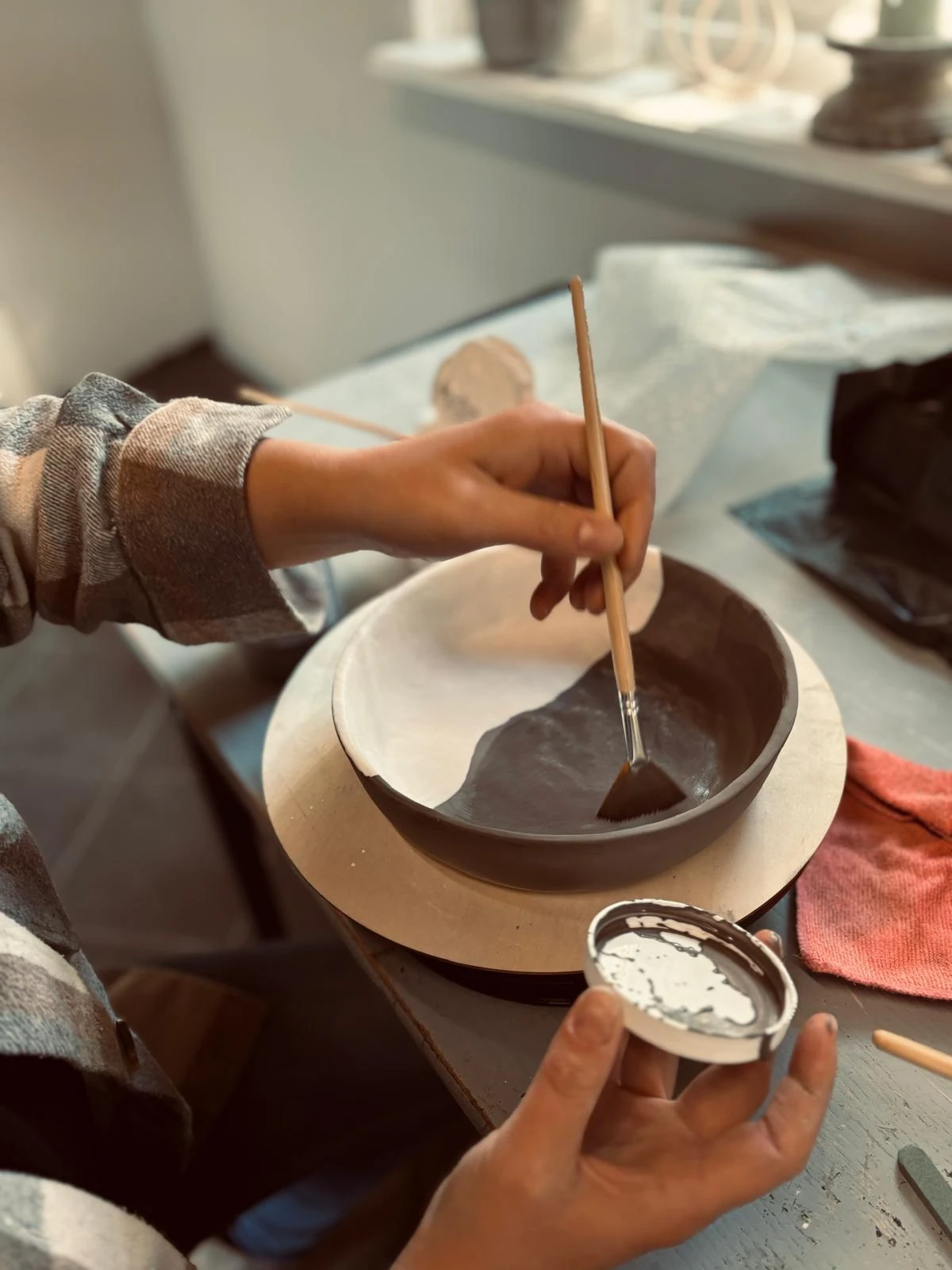 Deelnemer glazuurt keramiek tijdens een business workshop bij KeraMoniek